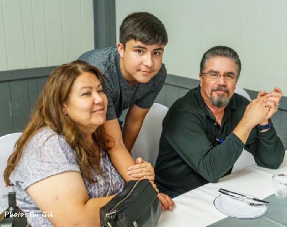 A trio of people sit at a table with white tablecloths.