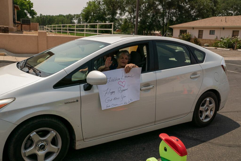A person in a white car holds a sign.