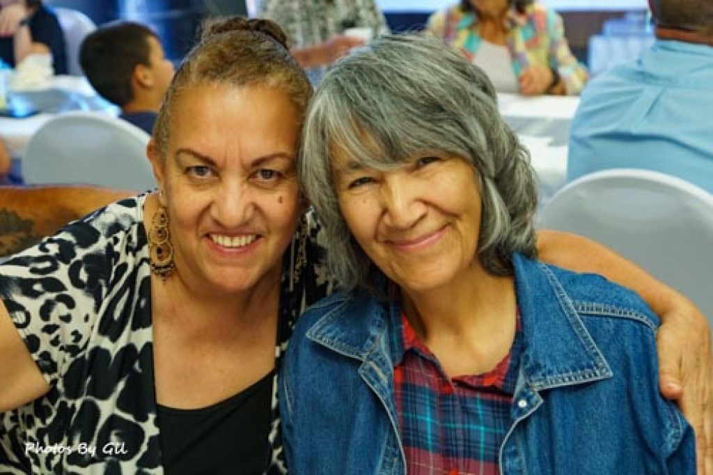 Two smiling women pose together at a social event. 