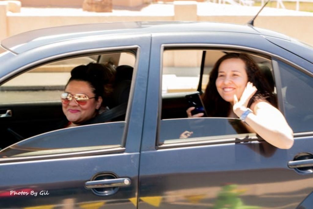 Two women are in a parked car, visible through open windows. 