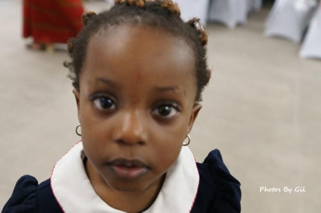 A young child with braided hair and hoop earrings.