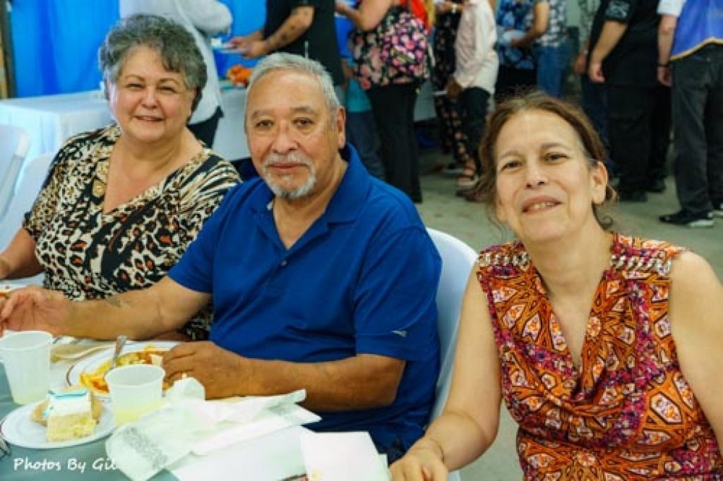 Smiling trio dining at an event. 