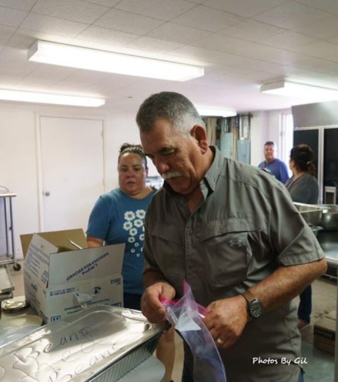 A man in a kitchen prepares food, sealing a plastic bag.