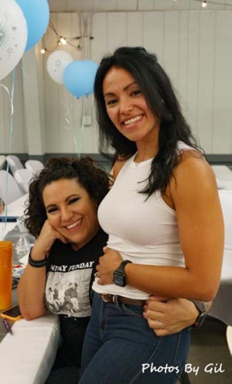 Two smiling women pose at a table.