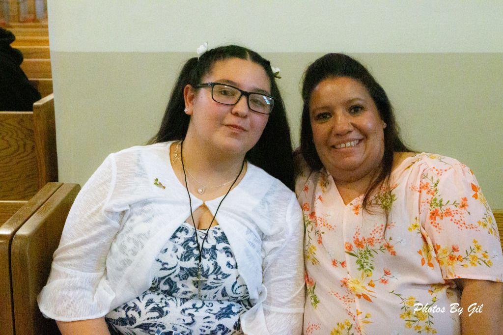 Two people sit closely on a wooden bench, smiling.