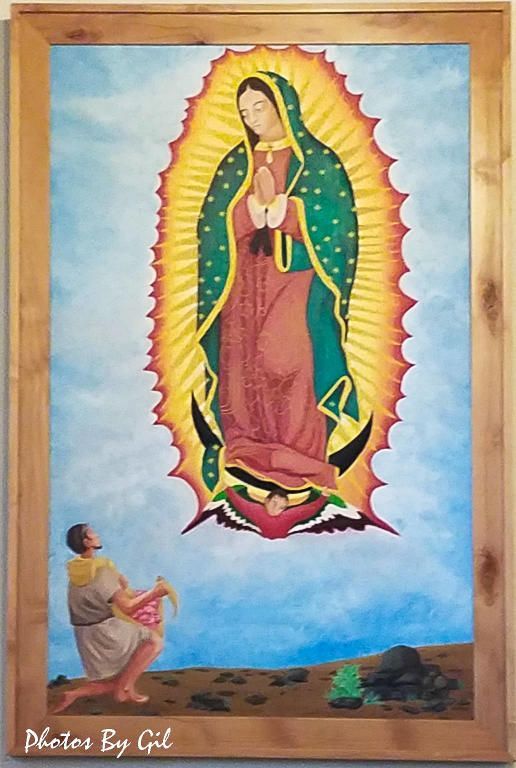 Painting of Our Lady of Guadalupe surrounded by a radiant aura, with a kneeling man.