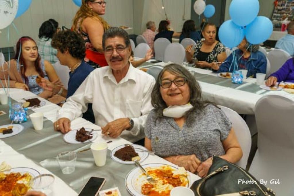 A joyful elderly couple sits at a festive table in a banquet hall.