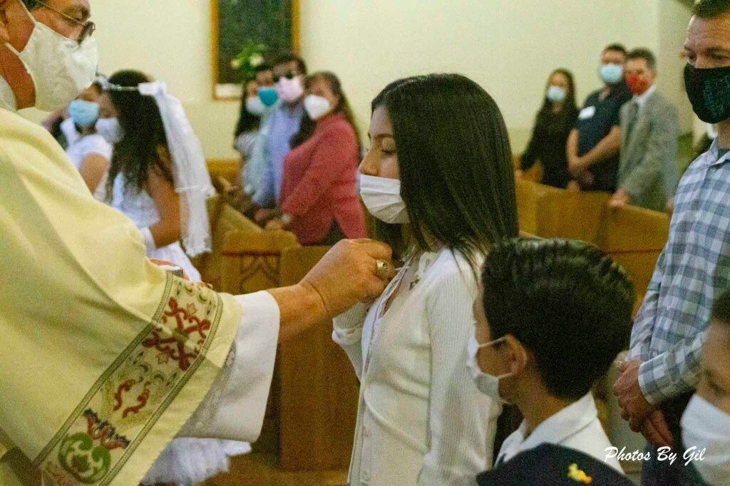 A priest performs a religious ceremony on a masked girl in a church. 