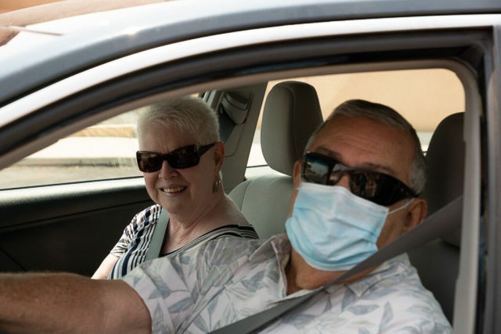 Elderly couple in a car, smiling.