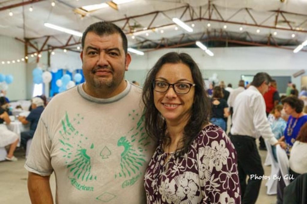 A smiling couple posing indoors at an event with festive balloons.