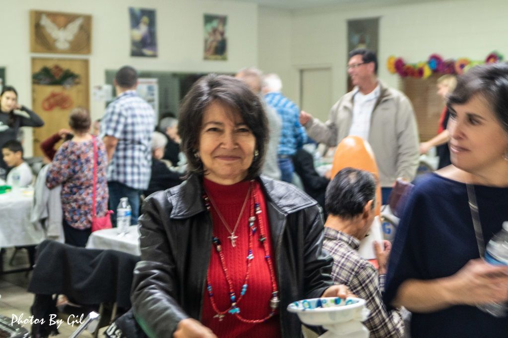 A smiling woman in a red sweater and leather jacket.