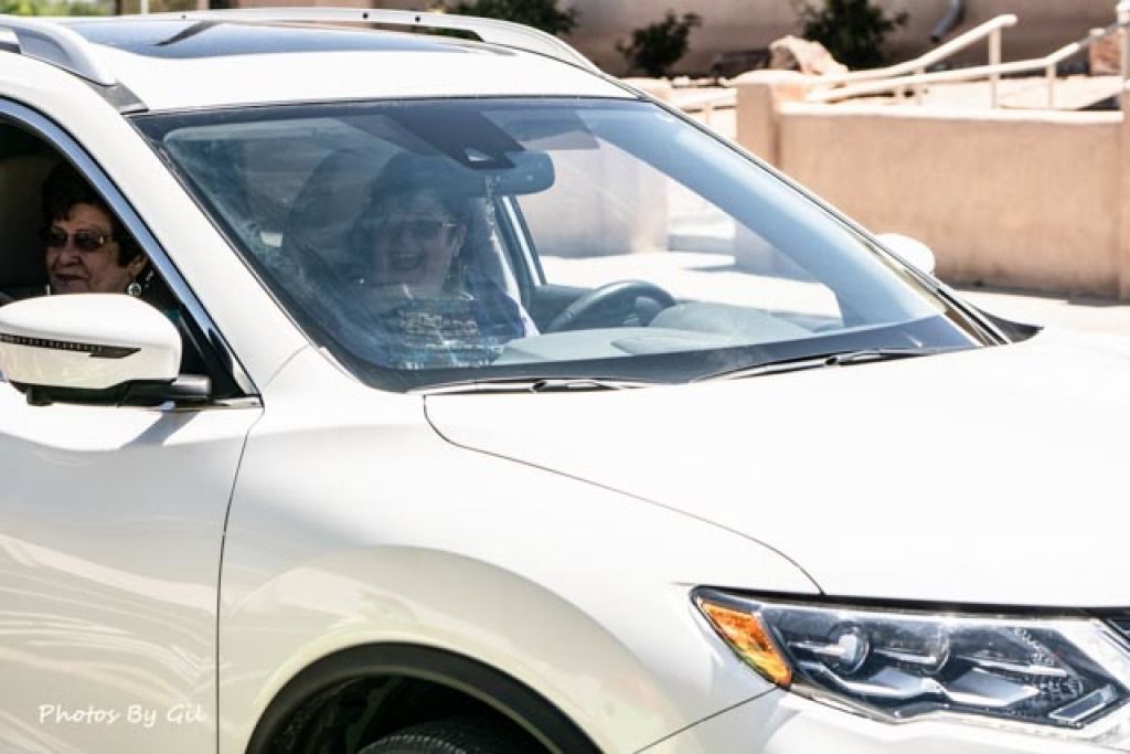 A white SUV is driving in bright sunlight. 