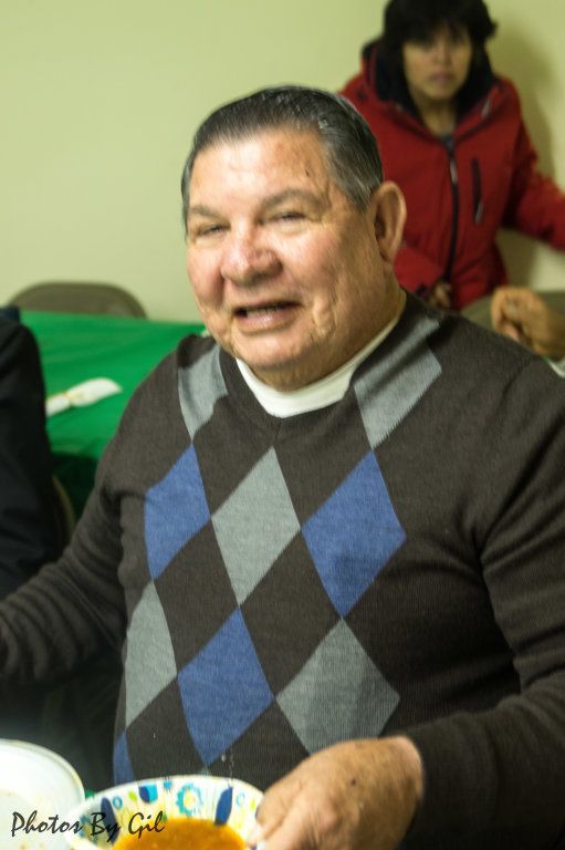 A smiling man in a brown argyle sweater.