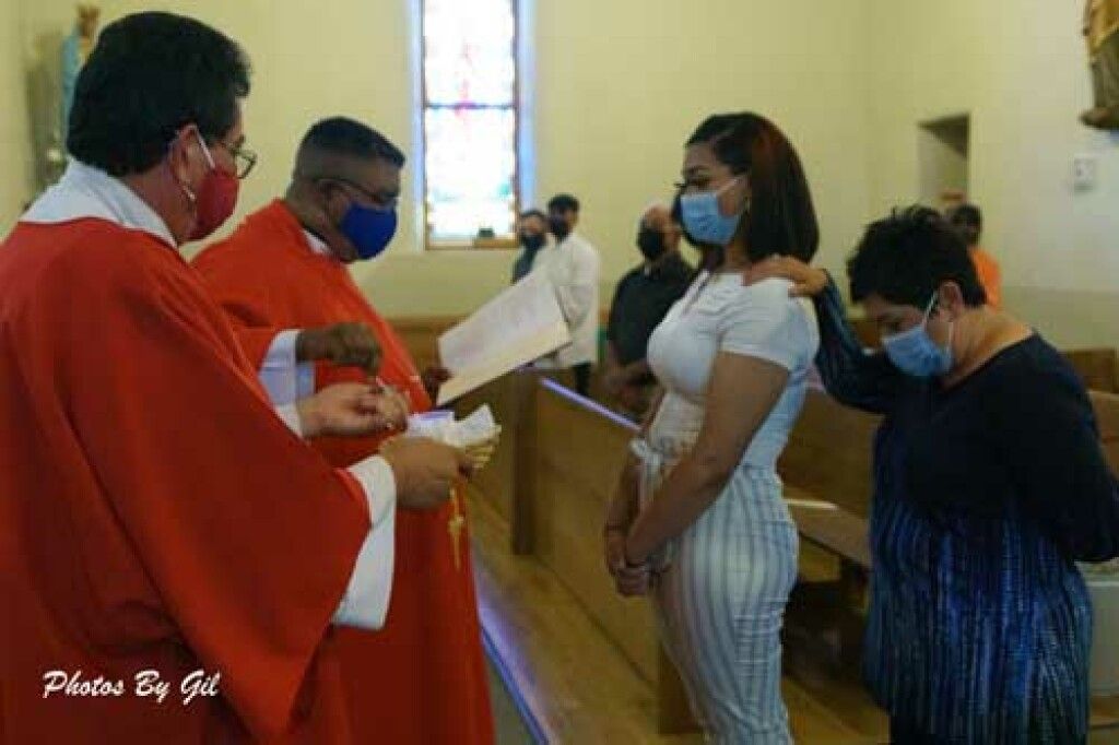A priest and an assistant in red robes and masks conduct a church ceremony.