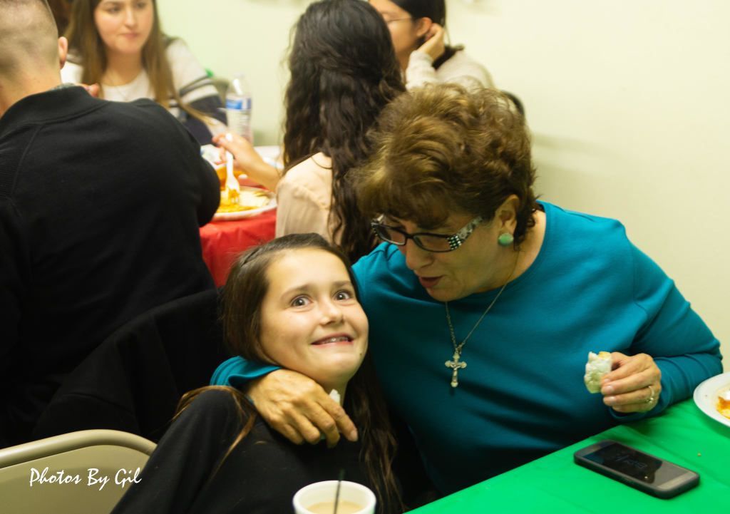 A joyful moment captured between an elderly woman and a child at a festive gathering.