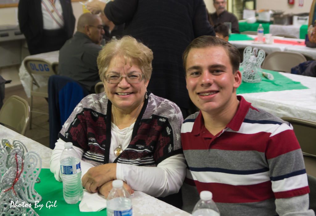Smiling elderly woman and young man sit together at a festive table.