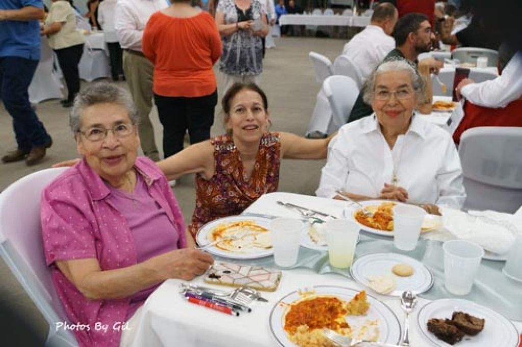 Three women are seated at a dining table during a social event. 