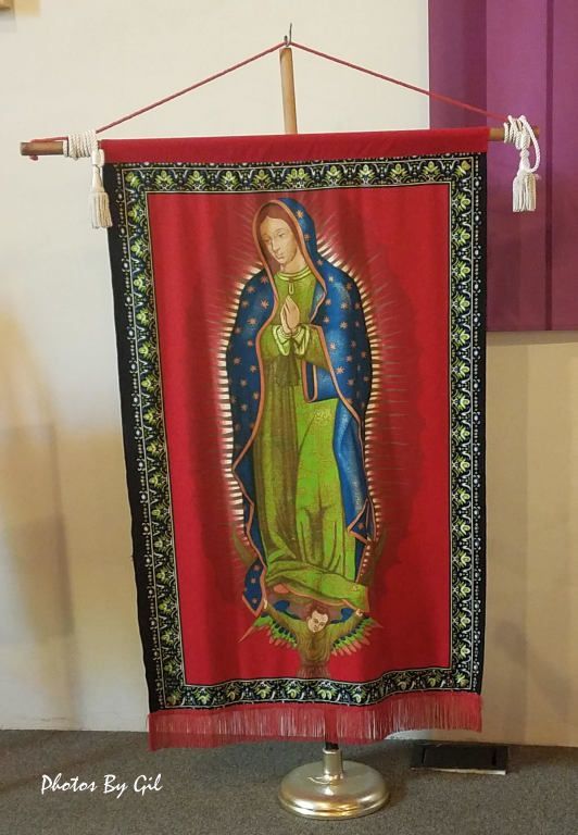 A vibrant tapestry on a stand depicts a religious icon in a green and blue robe.