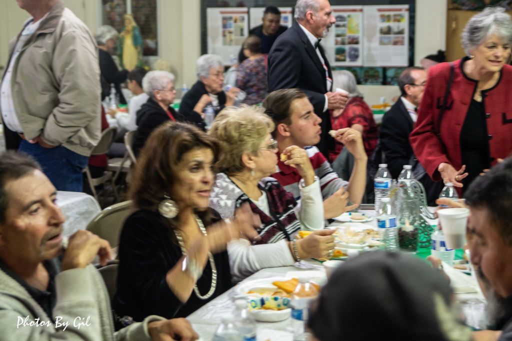 A lively gathering with people seated at a long table, engaged in conversation and dining. 