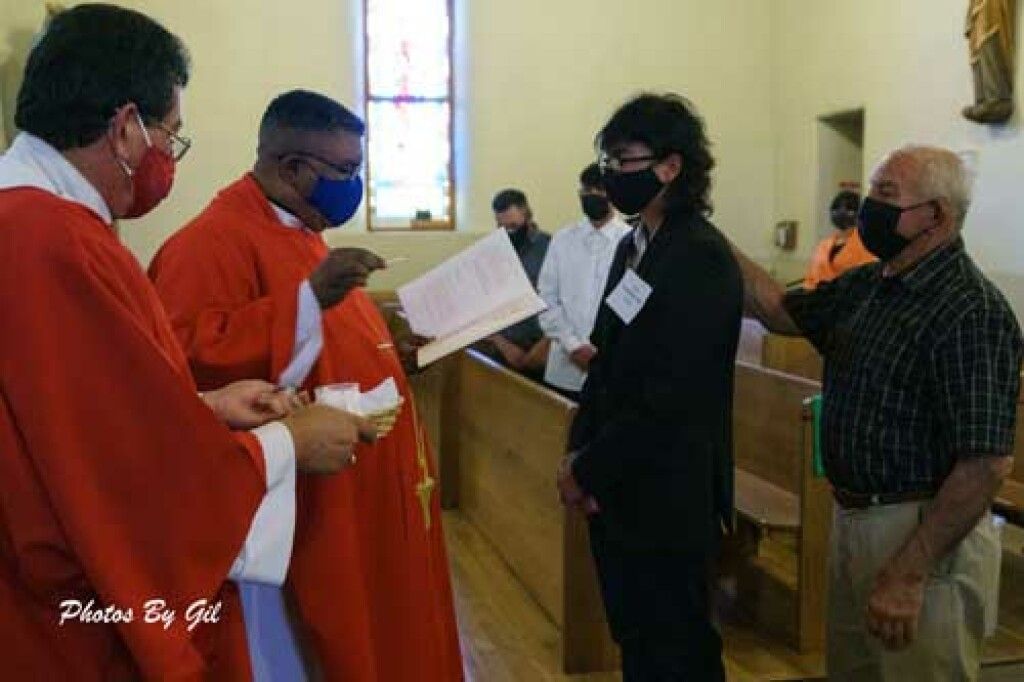 A priest in a red robe and mask holds a book.