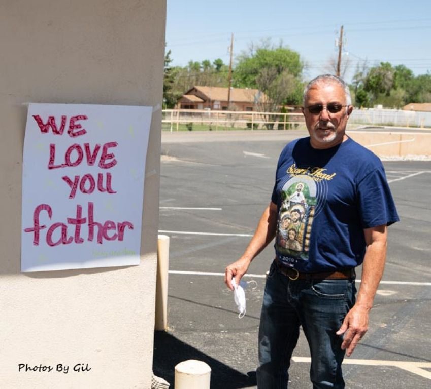 A man stands near a wall outside, next to a poster.