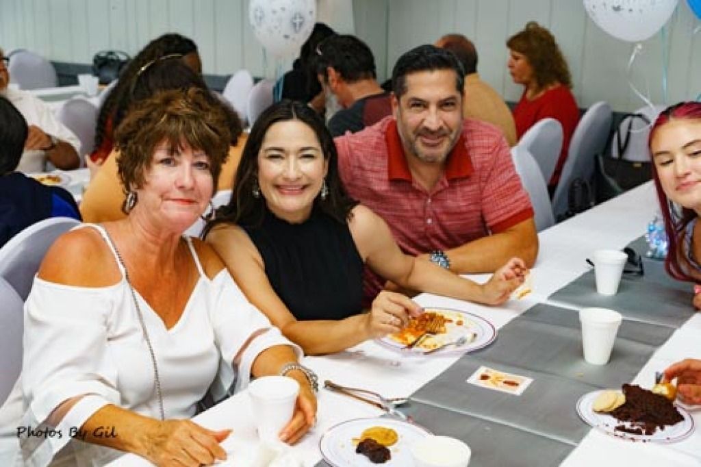 A group of people smiling at a table during a casual gathering.