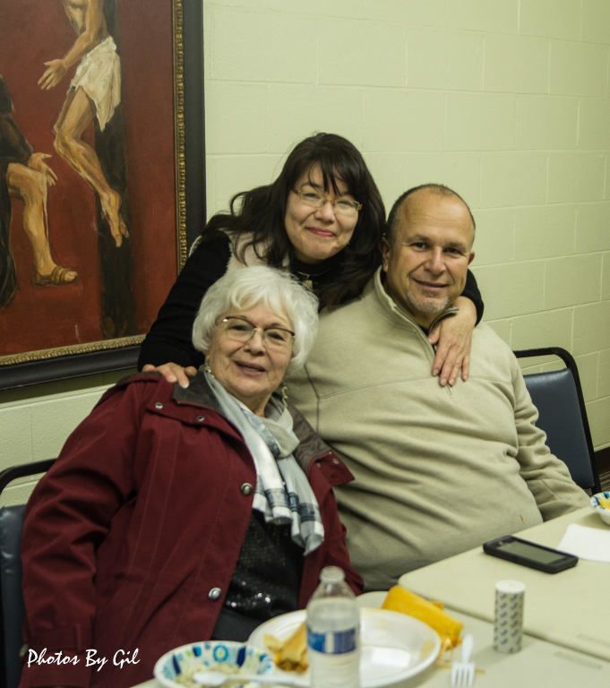 Three people posing at a dining table, smiling warmly. 
