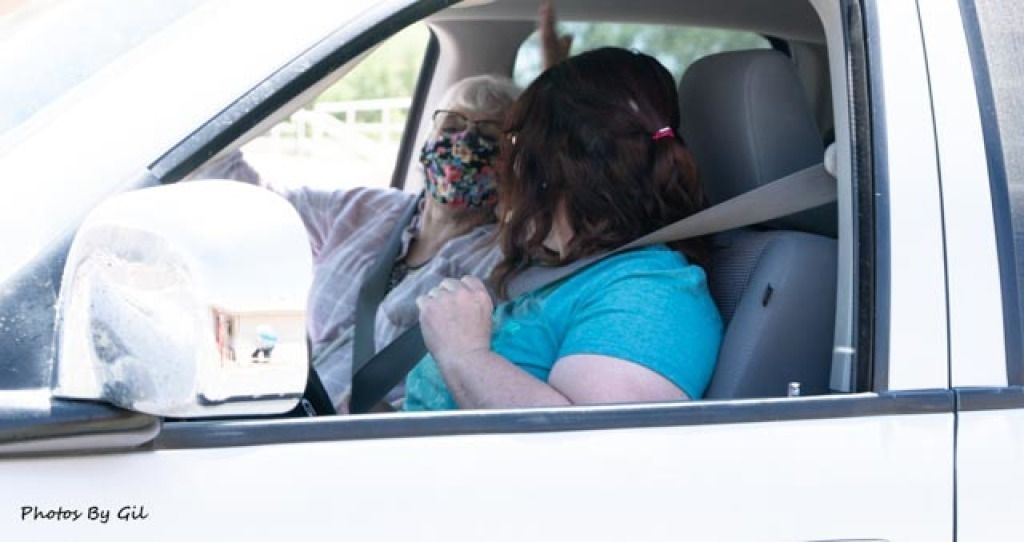 Two people in a white vehicle, both wearing seat belts.