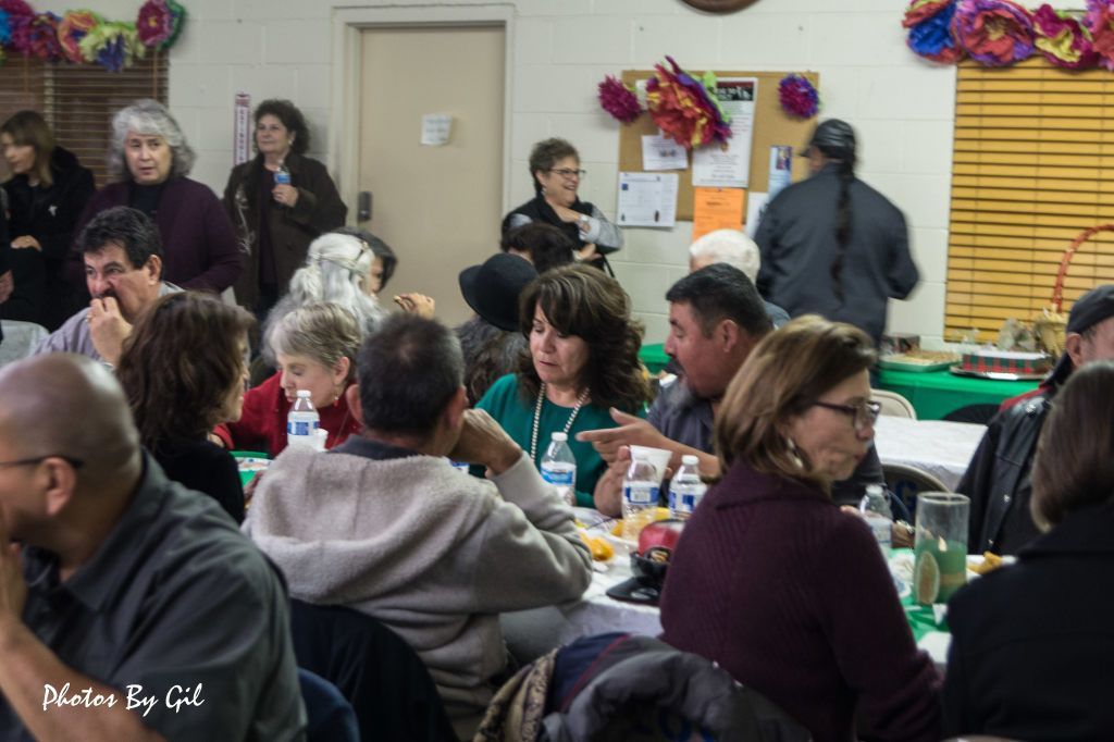 A group of people seated at tables in a community center.