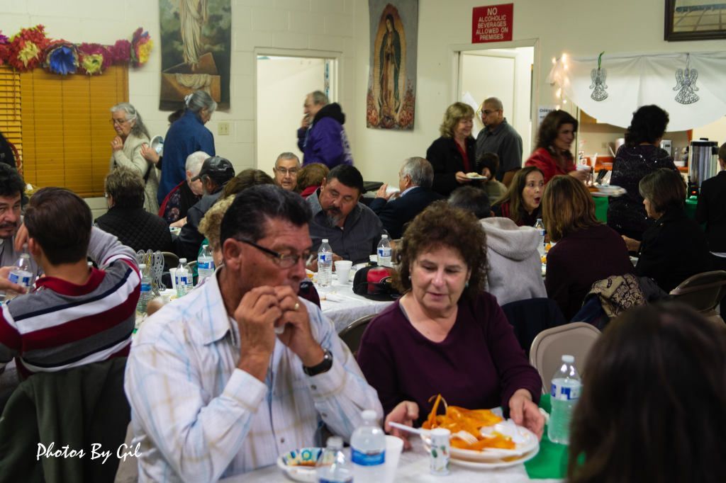 People gathered in a community hall enjoying a meal. 