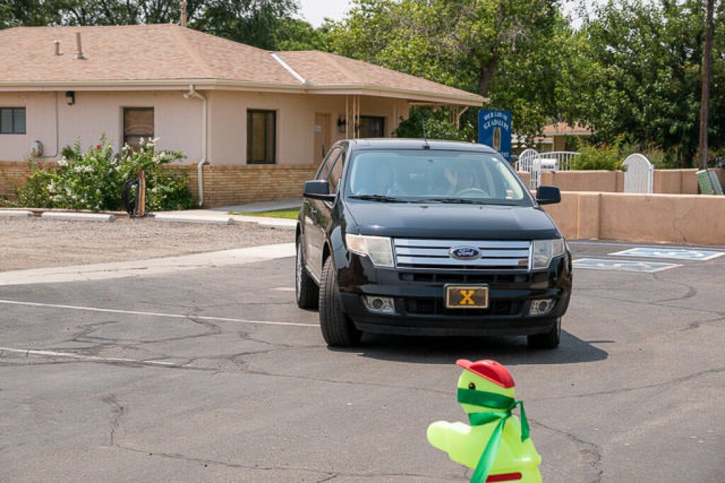 A black car with a license plate is parked diagonally in an empty lot.