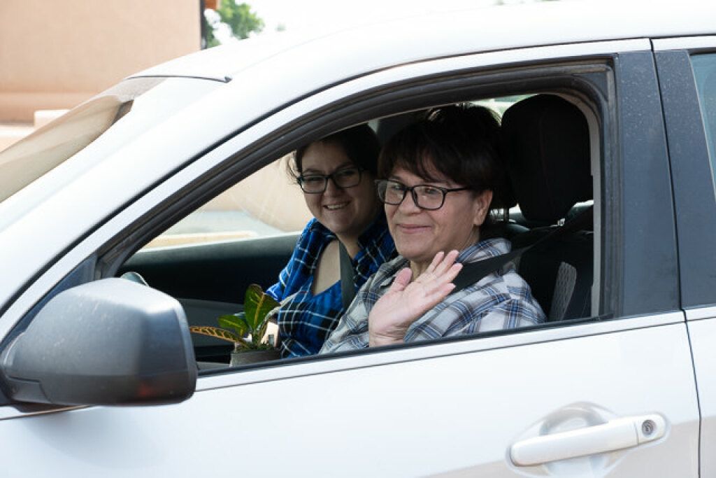 Two women sit in a white car. 