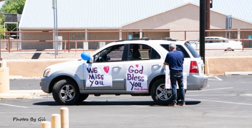 A man stands near a silver SUV in a parking lot.