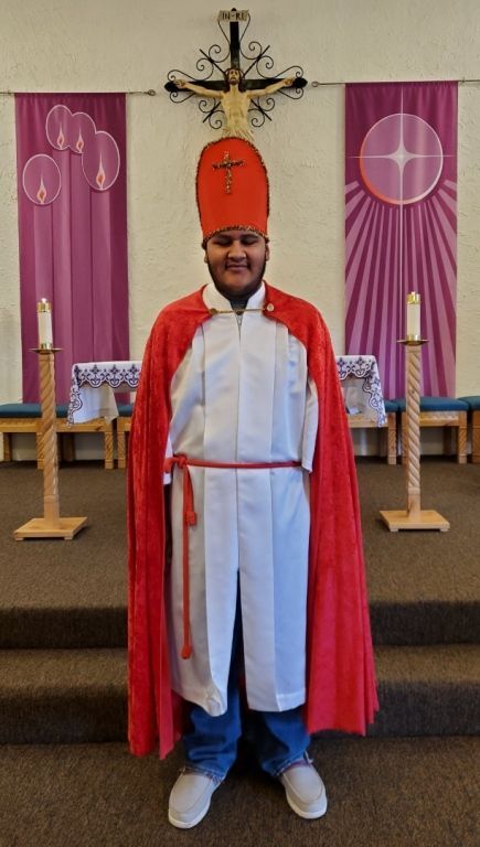 Daniel in ceremonial attire with a red cape.