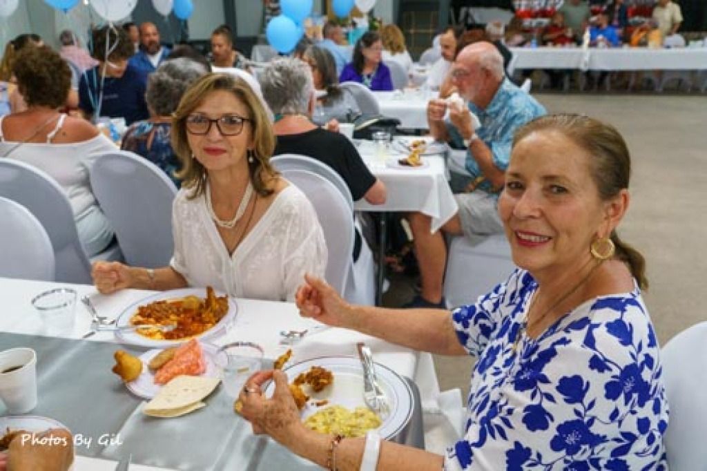 Two women sit at a dinner table, smiling and enjoying a meal together. 