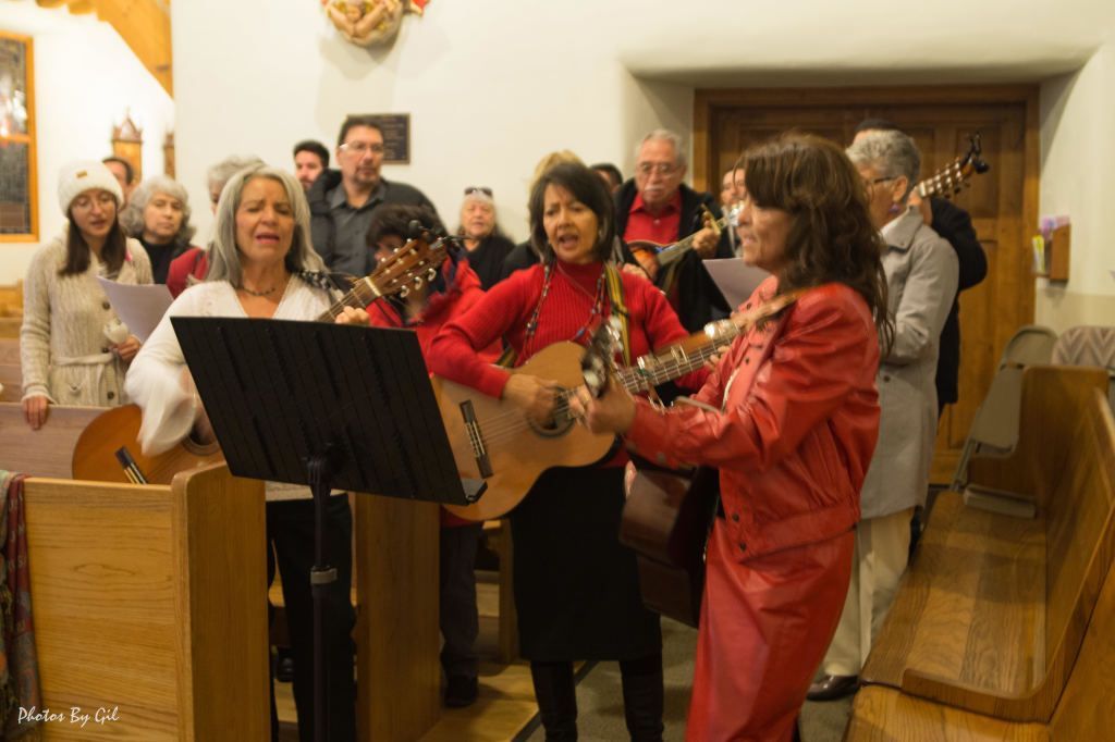 A group of people joyfully sing and play guitars in a warmly lit church. 