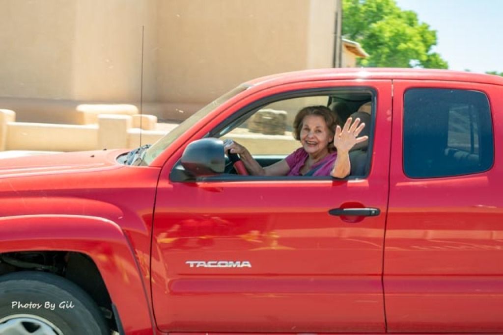 A woman in a red truck waves and smiles. 