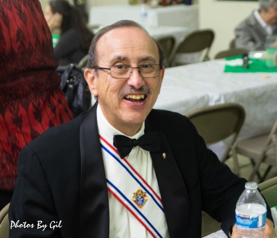 Smiling man in a black suit and bow tie.