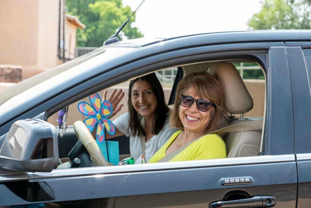 Two smiling women are inside a car. 