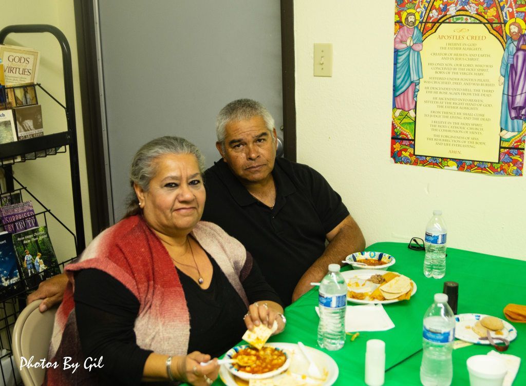 An older couple sits at a table with green tablecloth, smiling warmly. 