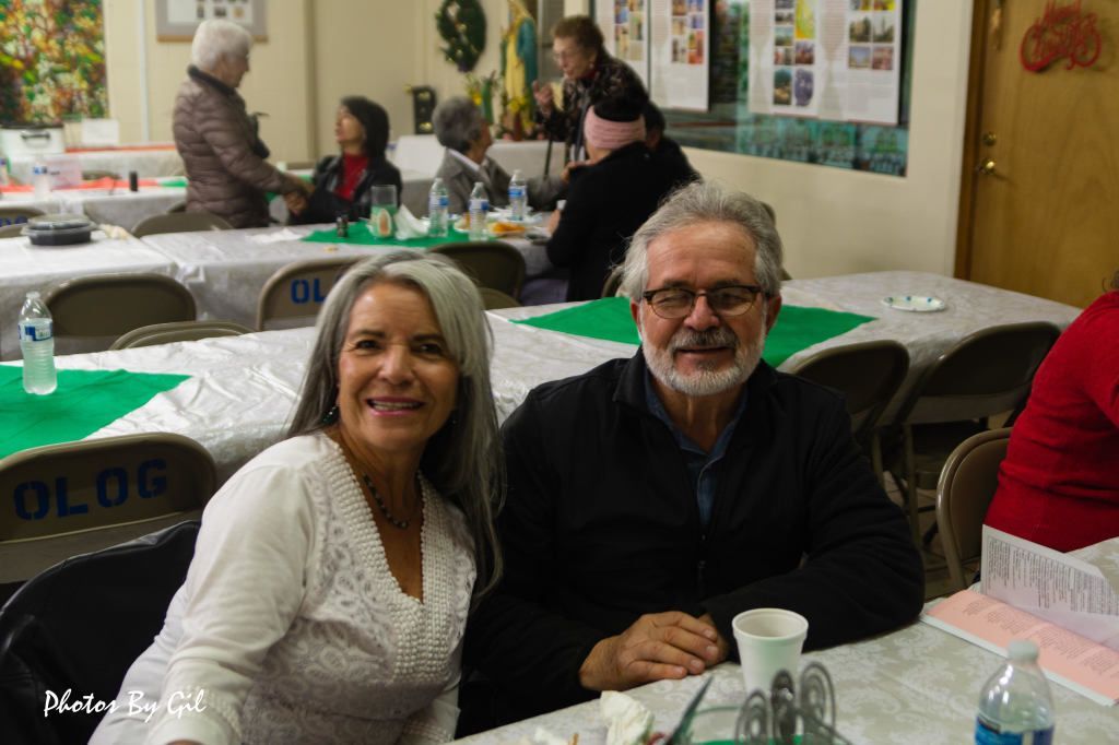 A smiling older couple sits at a festive table.