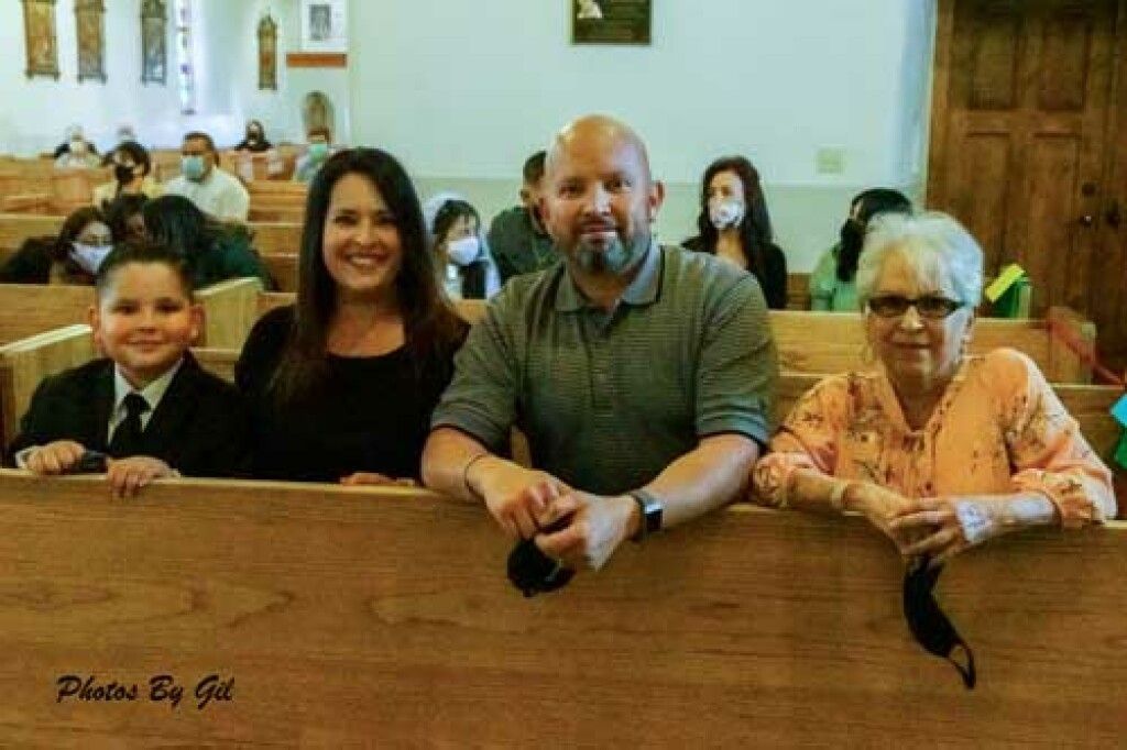 A family of four smiles while seated in a church pew.