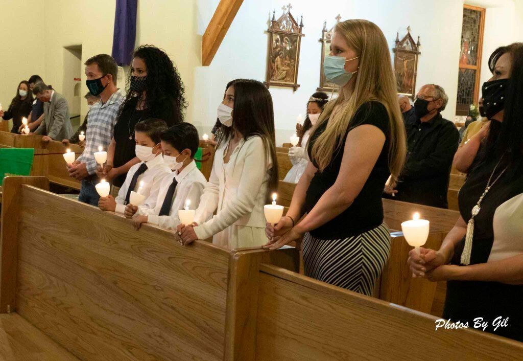 People in a church wearing masks and holding lit candles during a service. 