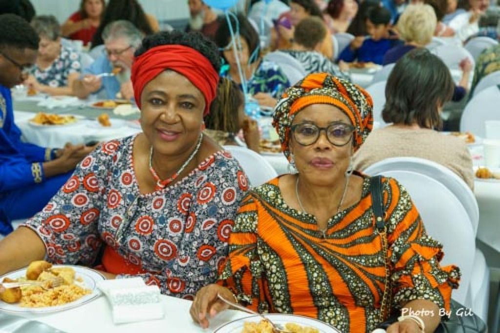 Two women sit at a table during a social gathering.