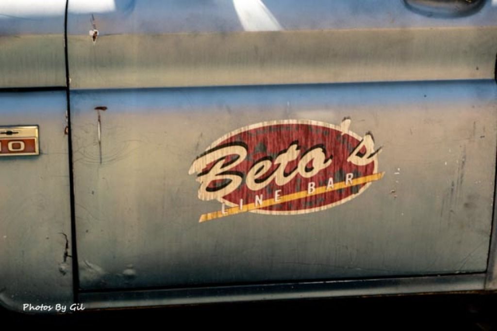 Close-up of an old, scratched truck door with a vintage Beto's Line Bar logo in faded colors. 