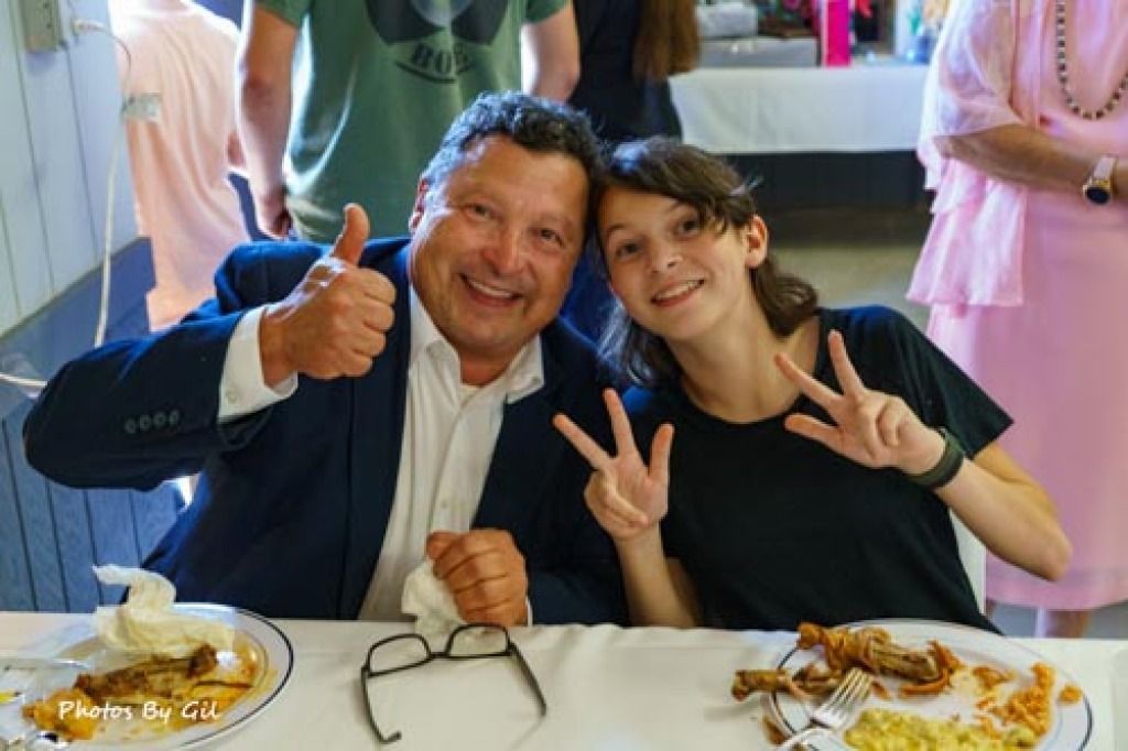 A man in a suit gives a thumbs-up, and a smiling child beside him flashes peace signs.