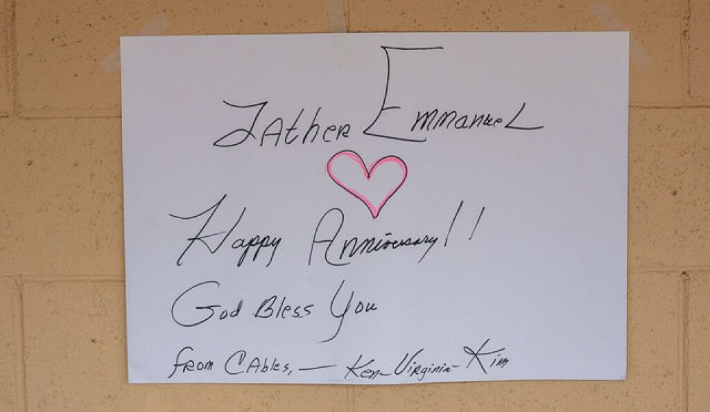 Handwritten anniversary sign on a white paper taped to a beige wall.
