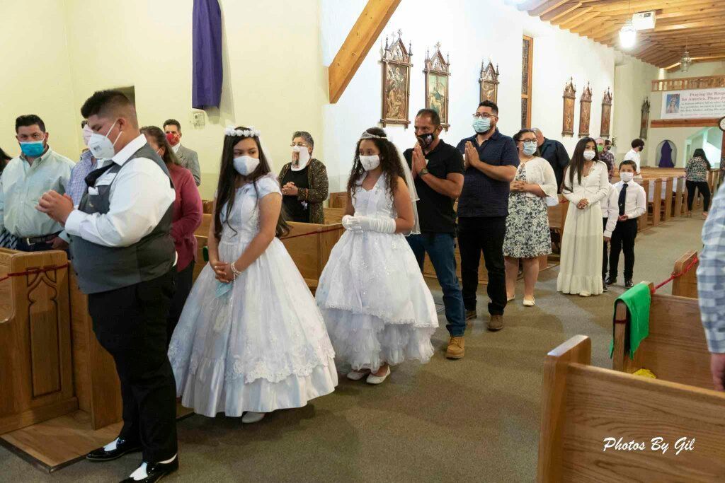 Children and adults, all wearing masks, stand in line at a church event.