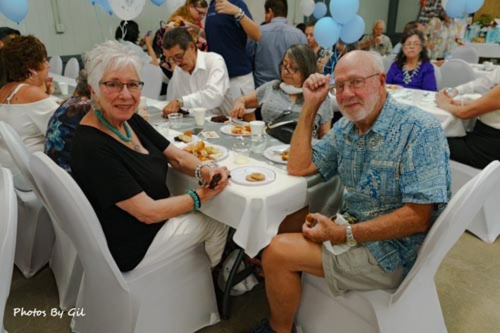 A joyful, lively gathering in a banquet hall with people seated at decorated tables. 