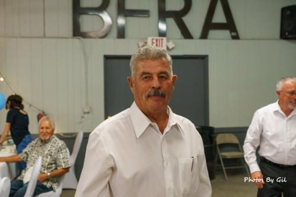 A man in a white shirt stands in a hall with BFRA on the wall behind him. 